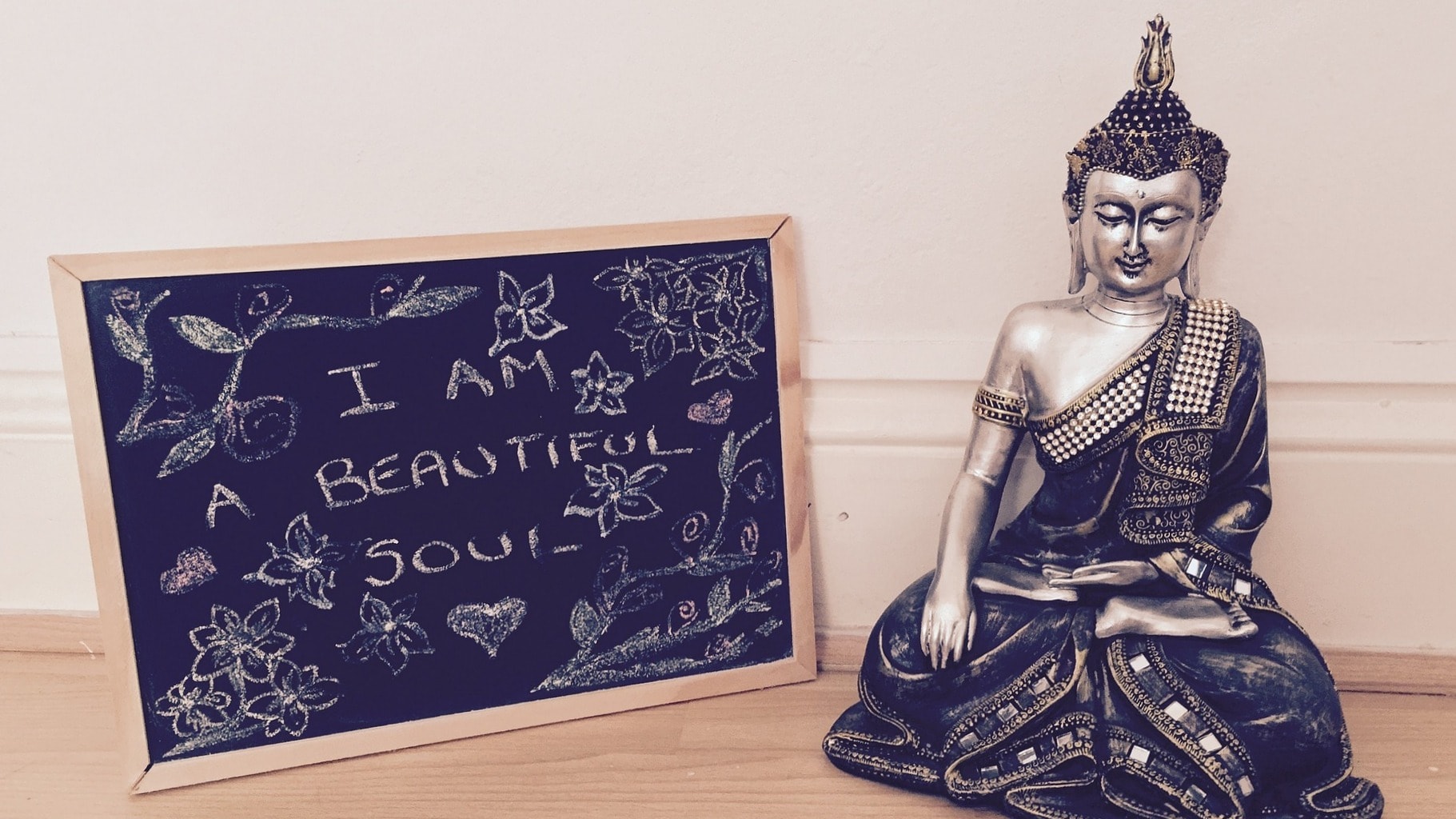 Buddha-Statue vor einer Wand; daneben eine Tafel mit der Aufschrift "I am a beautiful soul"