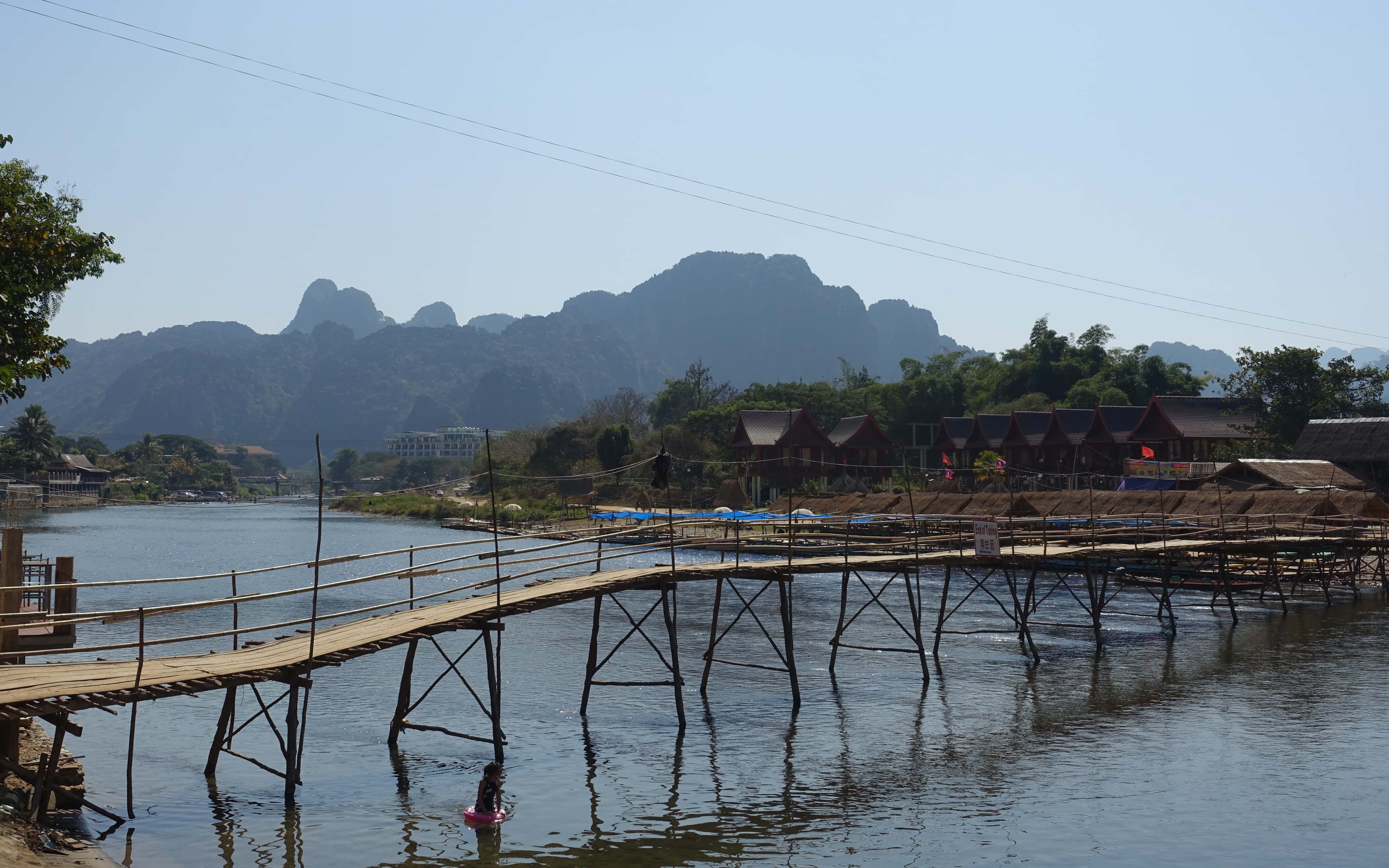 Eine hölzerne Brücke führt über einen Fluss in Laos