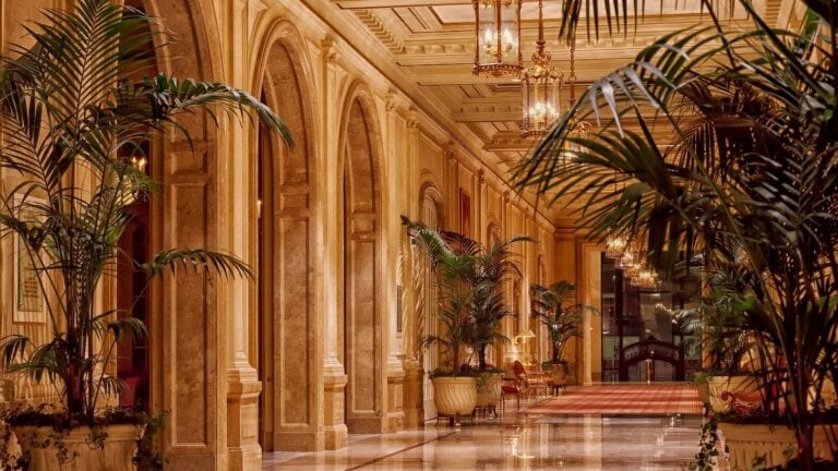 In einer marmornen Hotellobby stehen Palmen