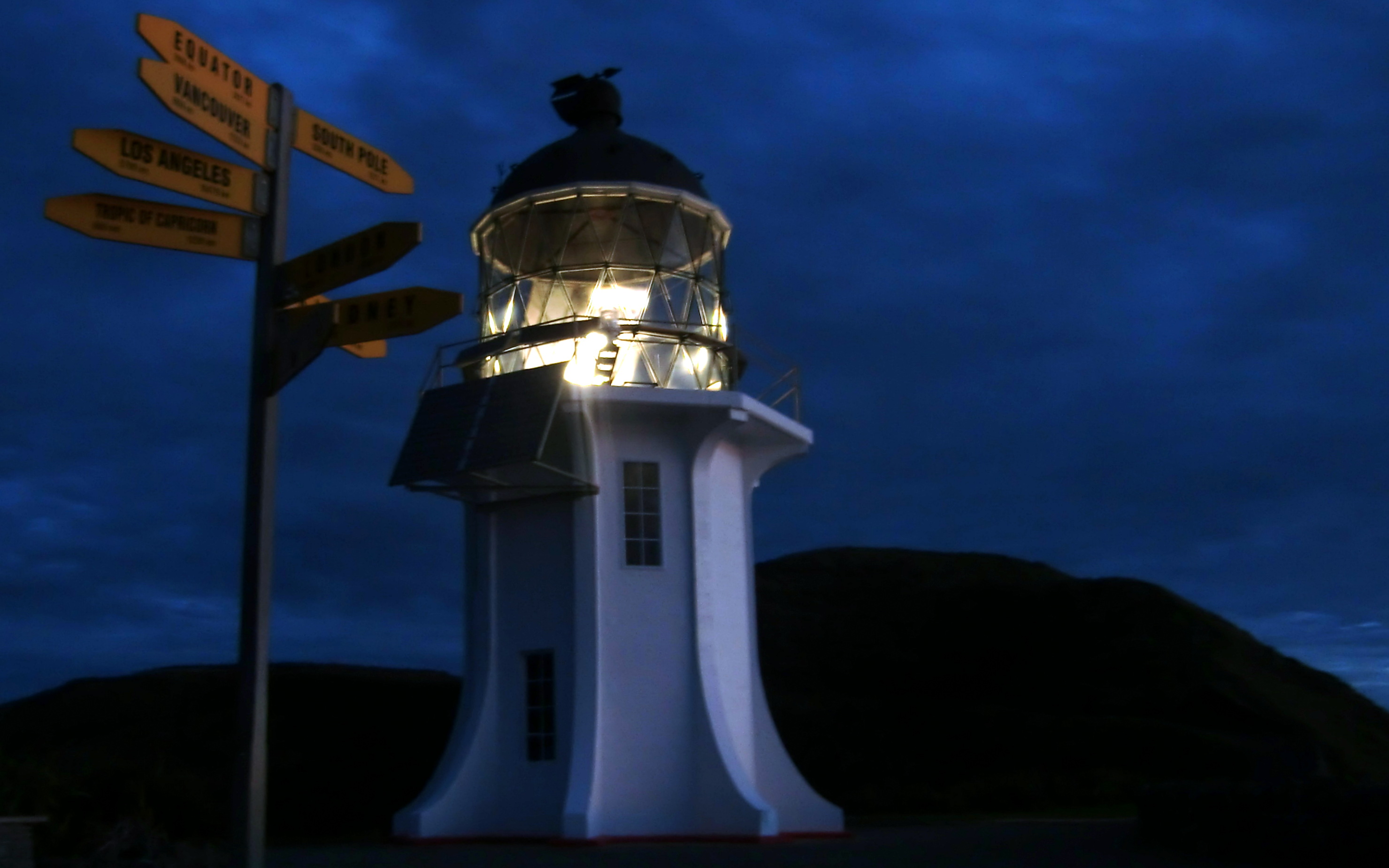 Der weiße Leuchtturm von Cape Reinga in Neuseeland strahlt bei Nacht.