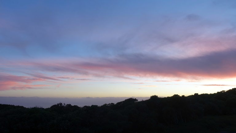 Kurz vorm Sonnenuntergang färbt sich der Himmel in Neuseeland lila. Nur ein schmaler goldener Strich ist am Horizont zu erkennen.