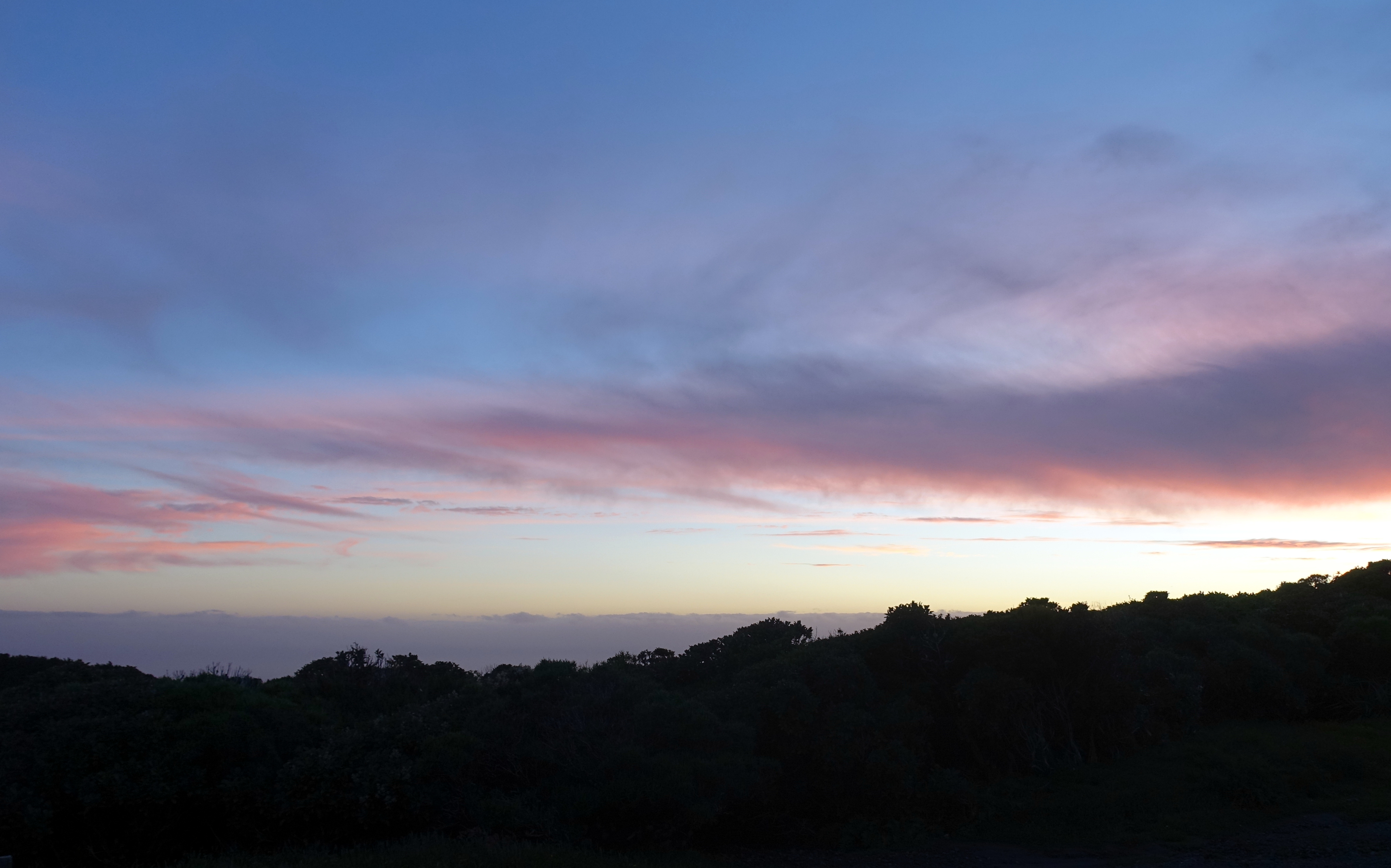 Kurz vorm Sonnenuntergang färbt sich der Himmel in Neuseeland lila. Nur ein schmaler goldener Strich ist am Horizont zu erkennen.