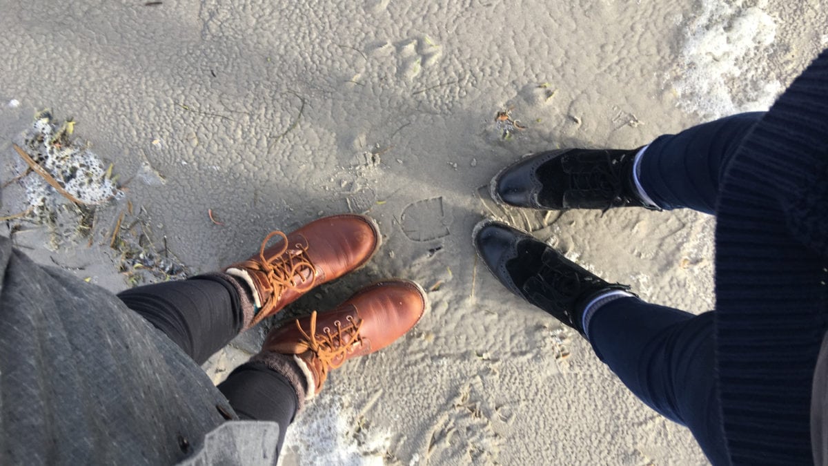 Zwei paar Stiefel stehen sich am Strand von Sankt Peter Ording gegenüber