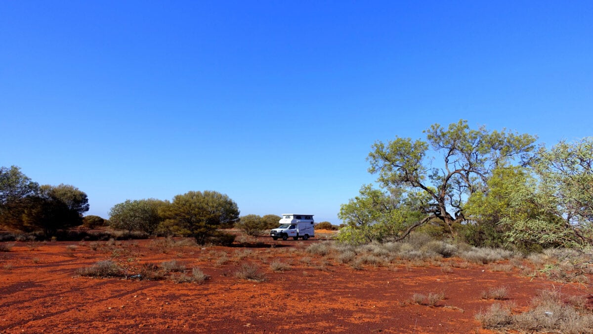 Suchbild: Der Campervan von Apollo umgeben von roter Wüste