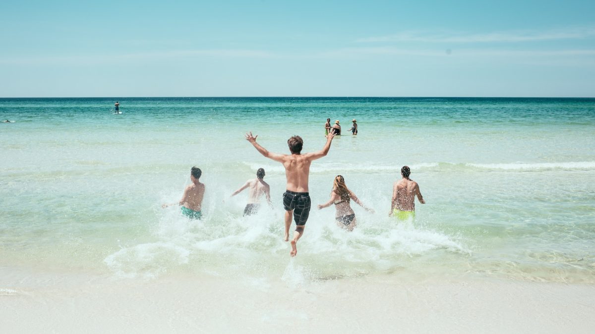 Junge Leute rennen ins Meer an einem Strand 