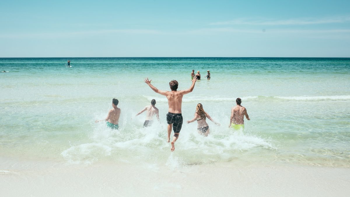 Junge Leute rennen ins Meer an einem Strand