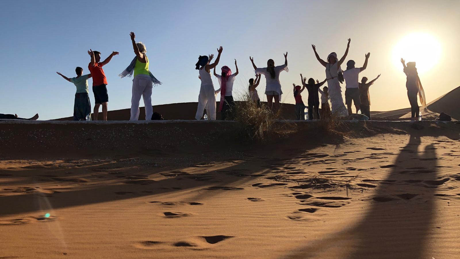 Eine Gruppe tanzt und macht Yoga in der Sahara