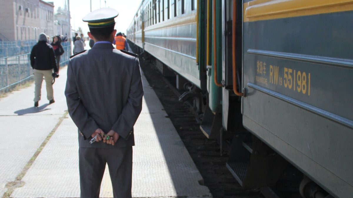 Chinesischer Schaffner vor der Transsibirischen Eisenbahn