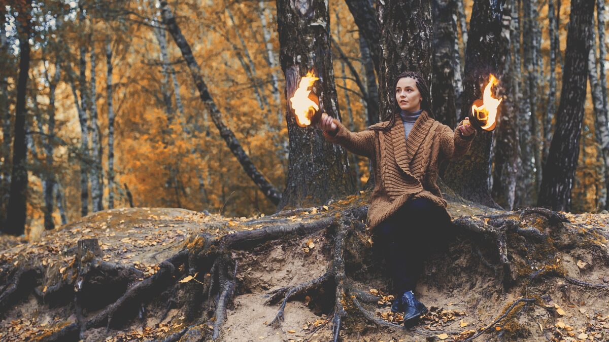 Eine junge Frau im Wald beschwört Feuer herauf